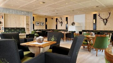 Ein modernes Restaurant mit Holzelementen und gemütlichen Sitzgelegenheiten. Die Wände sind mit kunstvollen Details und Bildern dekoriert.