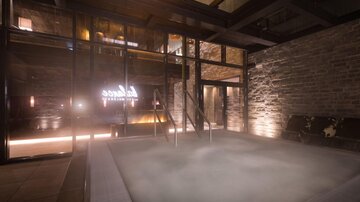 Ein entspannender Wellnessbereich mit einem Whirlpool und sanftem Licht. Die Wände sind aus Stein, was eine gemütliche Atmosphäre schafft.