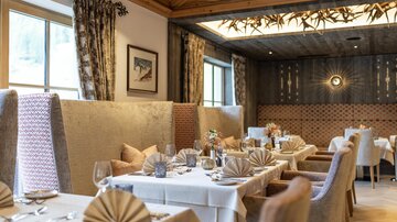 Ein elegantes Restaurant mit gemütlichen Sitzecken und schön gedeckten Tischen. Die Atmosphäre ist warm und einladend, ideal für ein feines Essen.