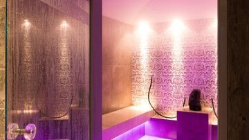 Ein eleganter Spa-Bereich mit sanften Lichtern in lila und einem modernen Design. Die Atmosphäre wirkt entspannend und einladend.