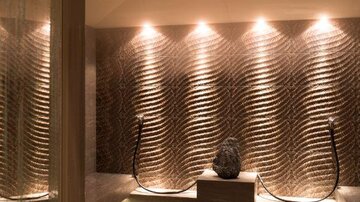 Ein eleganter Wellnessbereich mit sanft beleuchtetem, strukturiertem Wanddesign. Die Atmosphäre ist beruhigend und einladend.