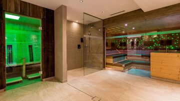 Ein modernes Wellness-Bereich mit entspannendem Ambiente. Es gibt einen Pool und eine Sauna mit sanften grünen Lichtakzenten.