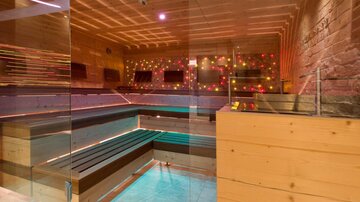 Ein moderner Wellnessbereich mit Holzvertäfelung und bunten Lichtern. Die Sauna ist hell und einladend gestaltet.