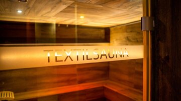 Eine Textilsauna mit warmem Licht und Holzverkleidung. Die Umgebung wirkt gemütlich und einladend.