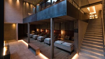 Ein moderner Wellnessbereich mit gemütlichen Liegen und stilvollem Holzdesign. Sanftes Licht schafft eine entspannende Atmosphäre.