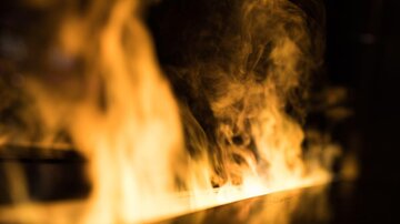 Ein Feuer mit lebhaften Flammen und Rauch. Die Atmosphäre ist intensiv und dynamisch.