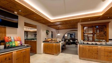 A cozy breakfast room with wooden furniture and elegant lighting. Various types of tea are provided on a table.