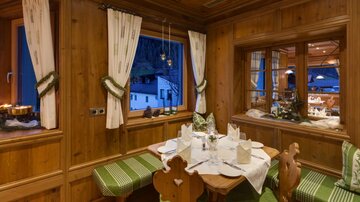 A cozy dining room with wooden paneling and large windows. The table is beautifully set and there is a warm, inviting atmosphere.