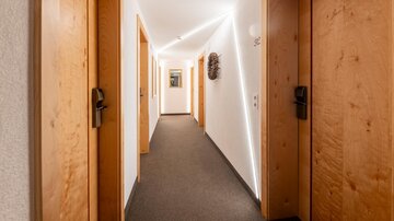 A bright hallway with wooden details and several doors. The light creates a modern and inviting atmosphere.