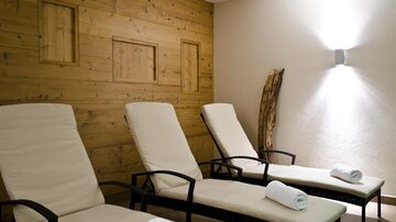 A relaxing wellness area with cozy loungers. The walls are made of wood, creating a calm atmosphere.
