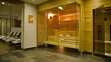 A modern wellness area with a glass sauna and wooden elements. The atmosphere is peaceful and inviting, perfect for relaxing.