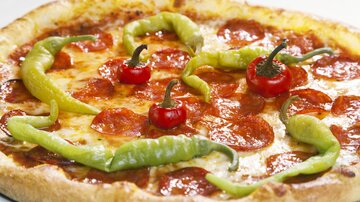 A pizza with pepperoni, spicy peppers, and fresh mozzarella. It is appetizingly and colorfully decorated.