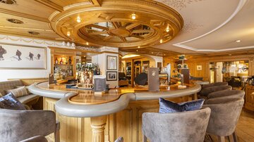 An elegant bar with a round bar counter and cozy seating. Wooden paneling and stylish lighting create an inviting atmosphere.