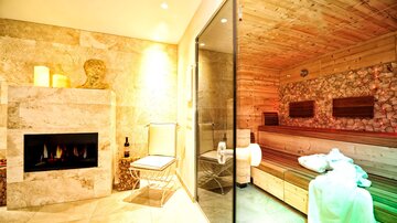 A cozy wellness area with a sauna and a fireplace. Soft lighting and natural materials create a relaxing atmosphere.