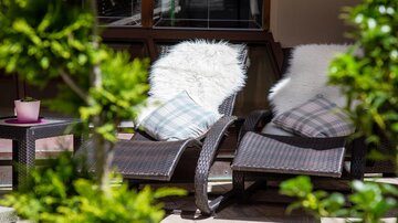 Relaxed loungers with soft cushions and blankets are surrounded by plants. Ideal for a cozy break outdoors.