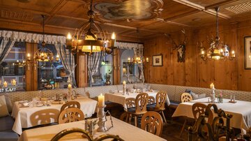 A cozy restaurant with wooden decor and elegant table settings. The warm lights create an inviting atmosphere.