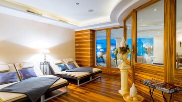 An elegant wellness area with wooden floors and lounge chairs. Large windows provide a view of a relaxing atmosphere.