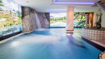 A modern swimming pool with gently flowing water and a relaxing atmosphere. The walls are decorated with picturesque landscapes.