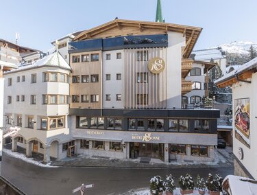A modern hotel building in a snowy environment. The sky is clear, and the architecture features a mix of traditional and contemporary design.