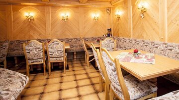 A cozy restaurant with wooden paneling and stylish seating. The tables are carefully set and appear inviting.