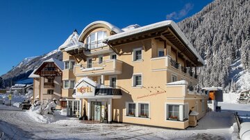 A charming hotel in a snowy landscape. The mountains and the clear sky give the scene an inviting atmosphere.
