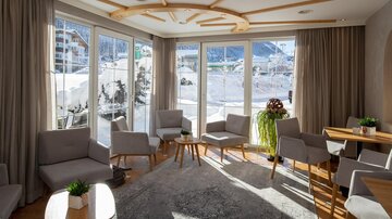 A bright and inviting lounge with large windows and a view of the snow-covered landscape. Cozy seating areas with modern furniture create a relaxed atmosphere.
