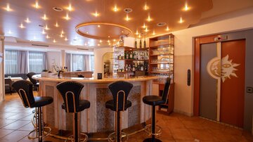 A stylish bar with round stools and an elegant counter. Soft lighting creates an inviting atmosphere.