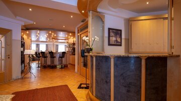 A modern hotel reception with an elegant reception desk. In the background, bar stools and an inviting lounge can be seen.
