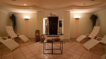 A relaxing wellness room with loungers and soft lighting. In the center, there is a water feature that creates a calming atmosphere.
