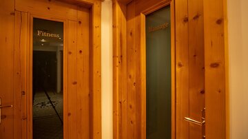 Two wooden doors mark the entrances to the fitness and wellness area. The doors are simply and modernly designed.