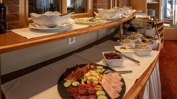 An elegant buffet with various cold dishes. On a table, there are arranged types of sausage, cheese, and vegetables.