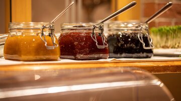 Three jars of jam in different colors are on a table. They are ready to be served and look inviting.