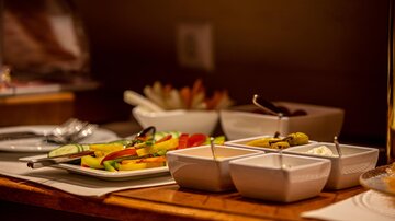 A buffet with fresh fruits and various sauces. Several bowls and cutlery are visible on the table.