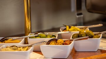 A selection of various pickled snacks in bowls. This includes olives, cucumbers, and peppers.