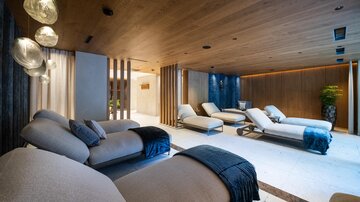 An elegant wellness area with comfortable loungers and warm wood decor. Soft lighting creates a relaxing atmosphere.
