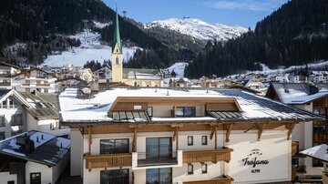 A charming hotel in a snow-covered mountain landscape. The impressive mountains and the church tower add a picturesque touch to the scene.