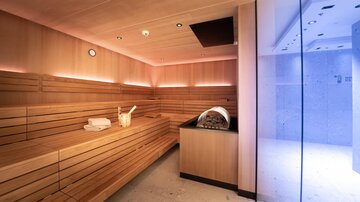 A modern sauna with wooden paneling and soft lighting. The room is cozy and inviting.