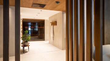 A modern reception area with wooden elements and soft colors. A plant and a bathrobe give the space an inviting character.