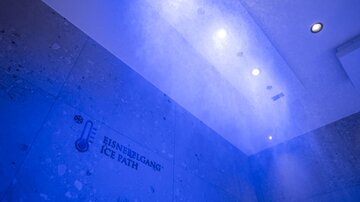 A modern room with blue light accents and a wall displaying the inscription "EISNIEBLGANG ICE PATH". It feels cool and inviting.
