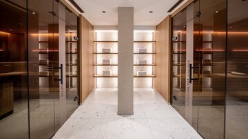 A modern room with glass walls and wooden shelves. The lighting is warm and creates an inviting atmosphere.