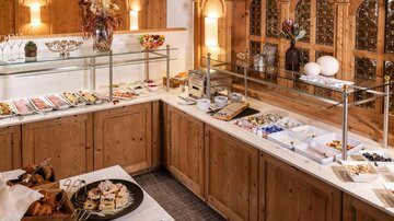A beautiful buffet with a variety of dishes in a cozy wooden setting. The tables are lovingly set and invite you to indulge.