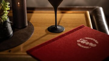 An elegant cocktail on a table. In the background, there is a stylish atmosphere with soft lighting.