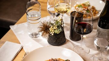 An elegant table setting with a plate of rice and vegetable dish. In addition, wine glasses and water pitchers are arranged on a nice table.