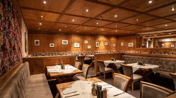 A cozy restaurant with wooden walls and bright ceiling lights. The tables are set and the seating provides an inviting atmosphere.